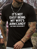 Men's T-Shirt Its Not Easy Being My Wifes Arm Candy Here I Am Nailing It Bold White Lettering On Solid Black Cotton Shirt